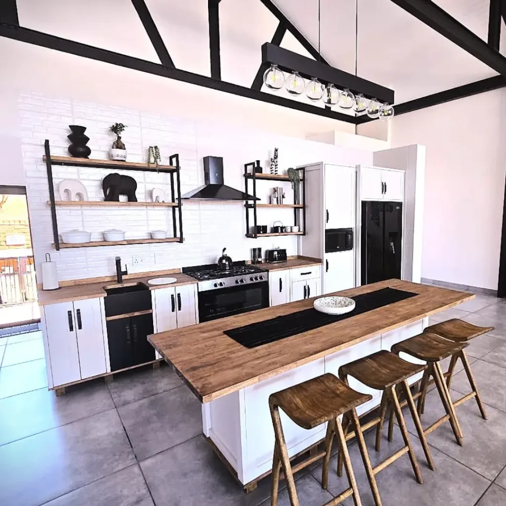 Modern kitchen with white cabinets, wood countertops, open shelving, and wooden bar stools at a center island.