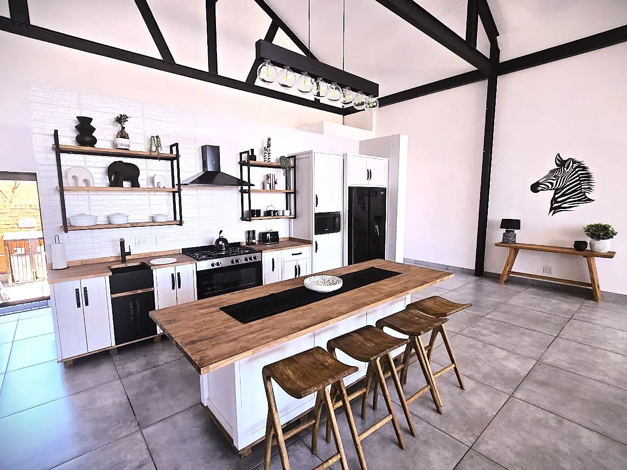 Modern kitchen with white cabinets, wood countertops, open shelving, and wooden bar stools at a center island.