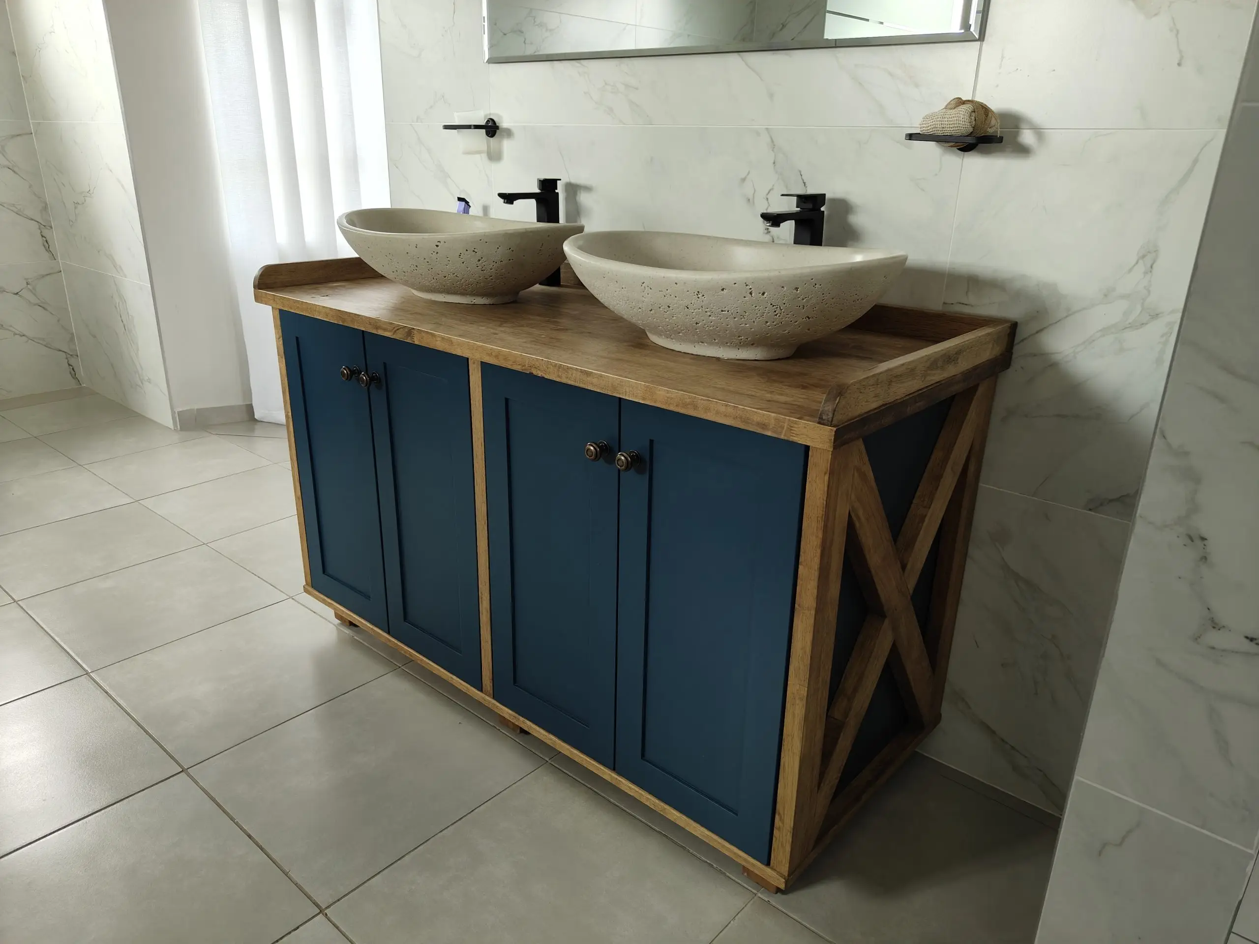 Bathroom vanity with blue cabinet doors and two stone vessel basins.