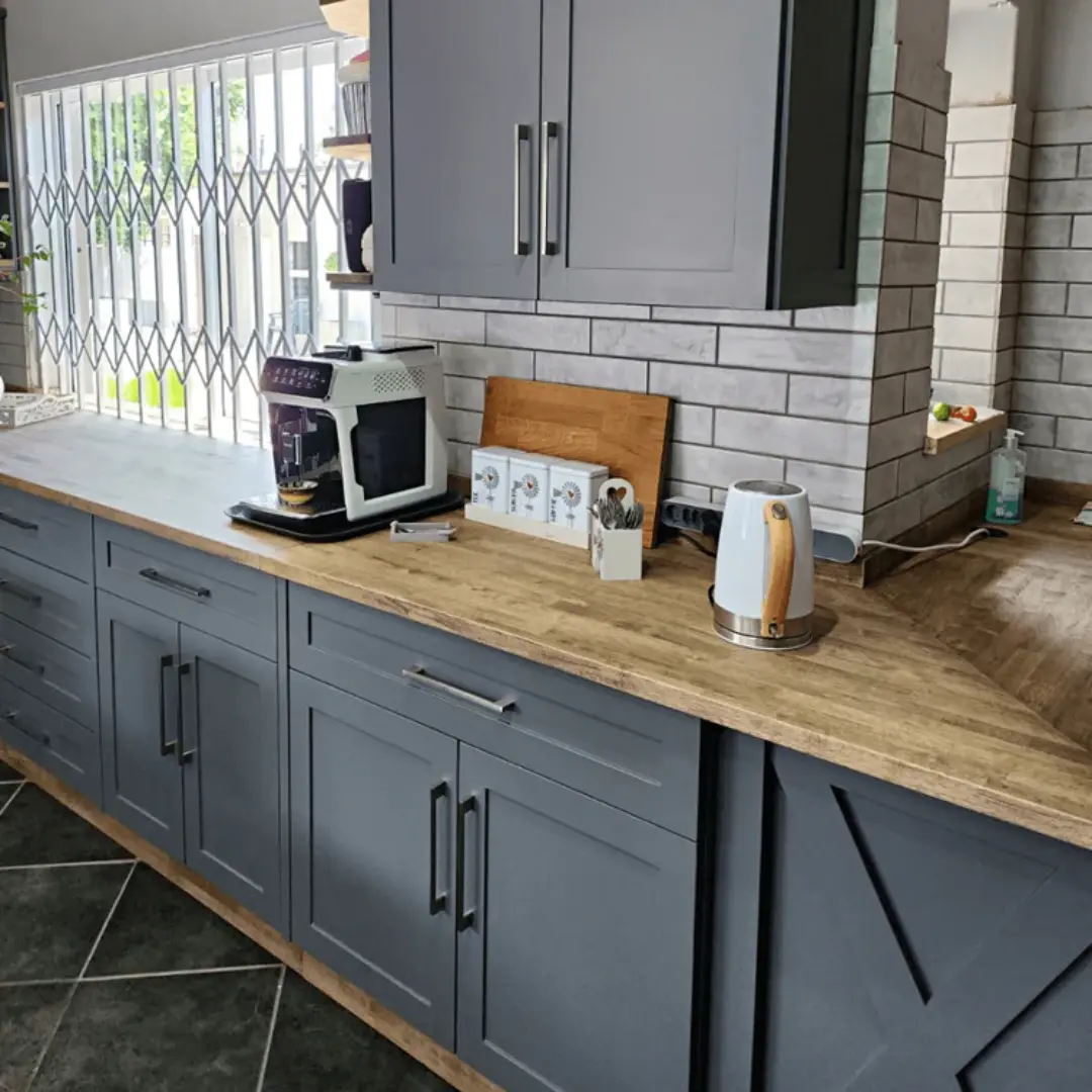 Kitchen interior featuring charcoal grey cabinets and wooden countertops,