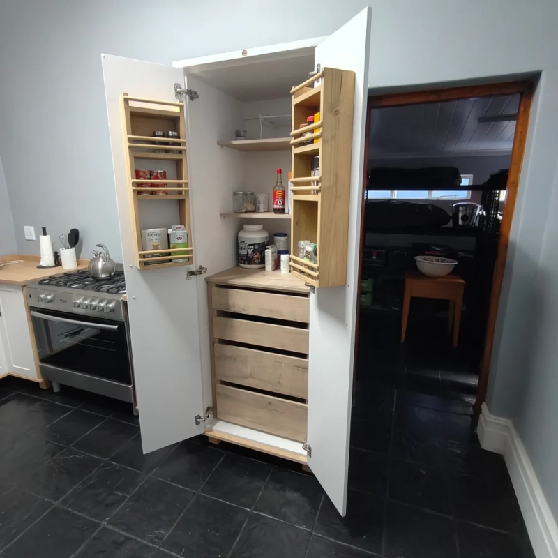 Deluxe Pantry White Open Right A right view of an open white deluxe pantry with shelves and spice racks in a kitchen