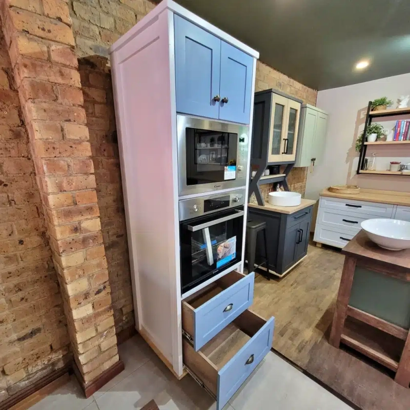 An open blue eye level oven unit with drawers in a show room