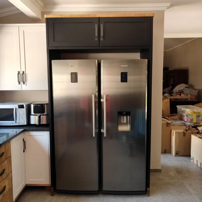 A black fridge house unit in a kitchen with two fridges in the middle