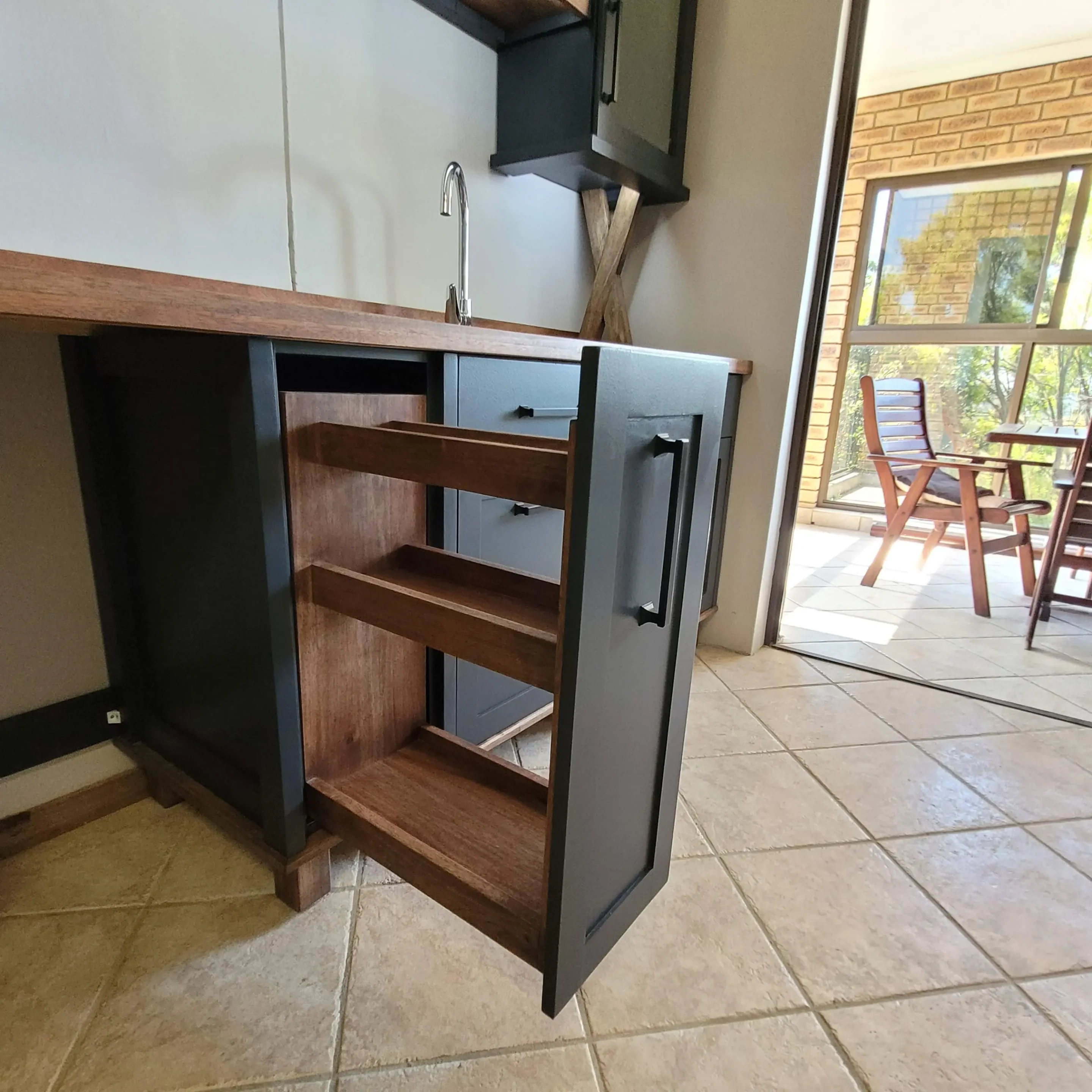 Black Open Spice Rack Showroom Left A black full kitchen set with drawers, a pantry cabinets, a split corner pantry a kitchen island and a double sink