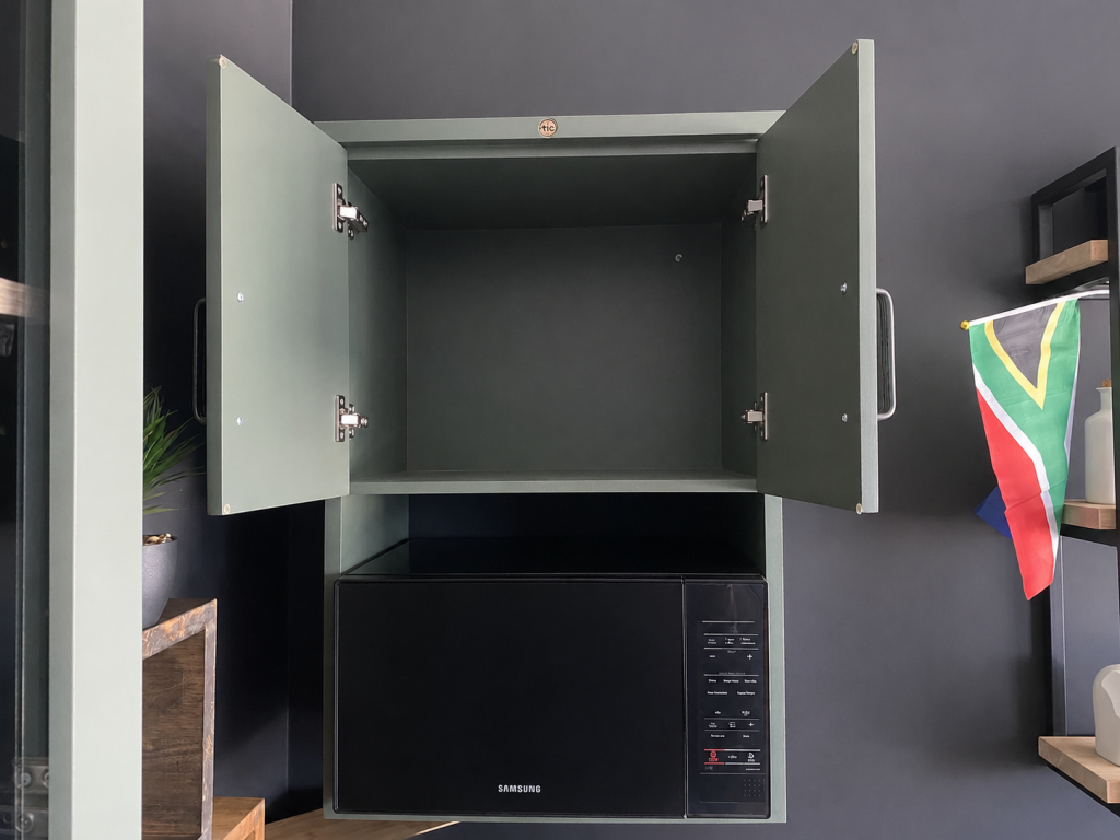 A Front View of An Open Green Microwave Wall Cabinet In A Showroom