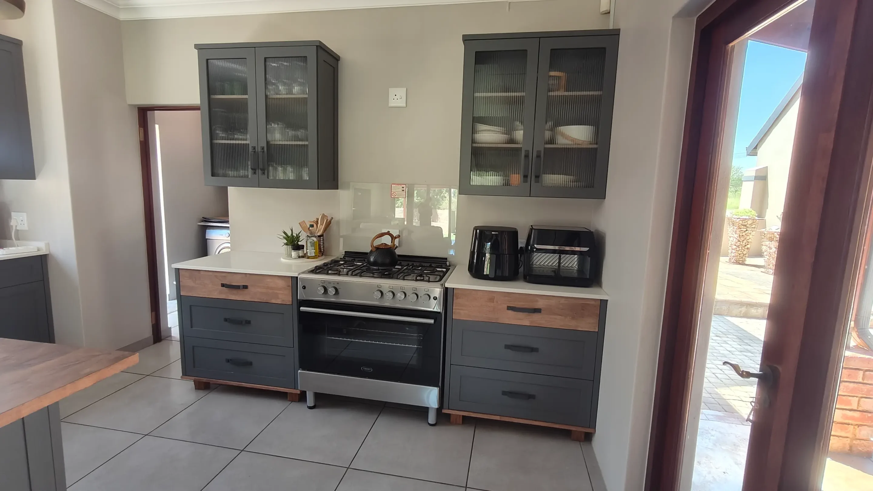 Two Black Double Door Wall Cabinets Fluted Glass Kitchen A Modern Kitchen With Two Black Double Door Wall Cabinets With Fluted Glass and Two Black Three Pot Drawers Along The Side Of A Stove